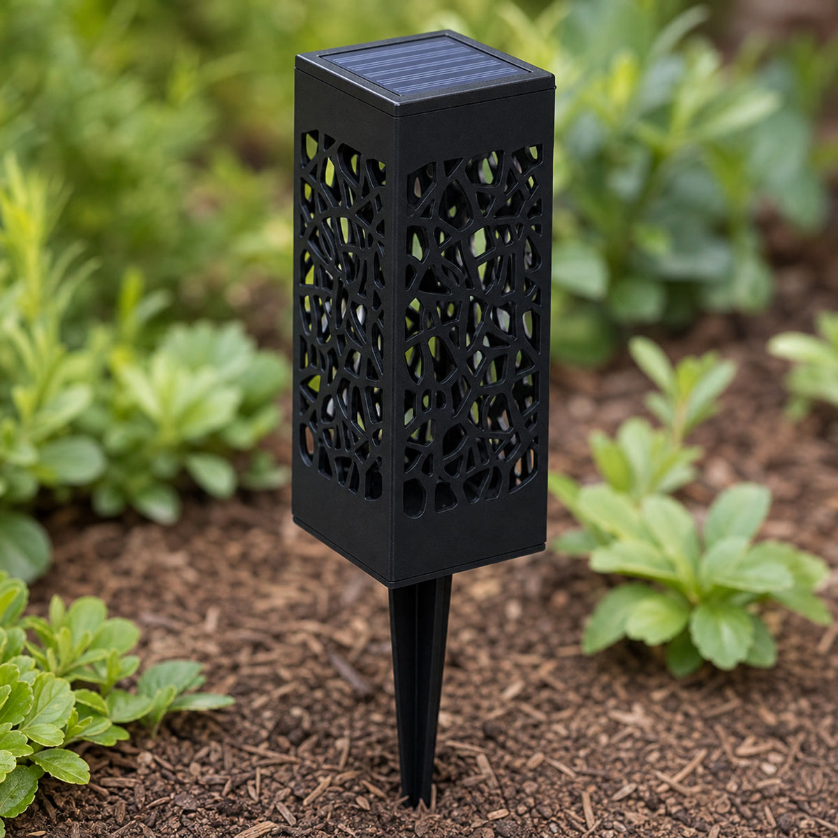 Close view of a black filigree solar pathway light with a top solar panel