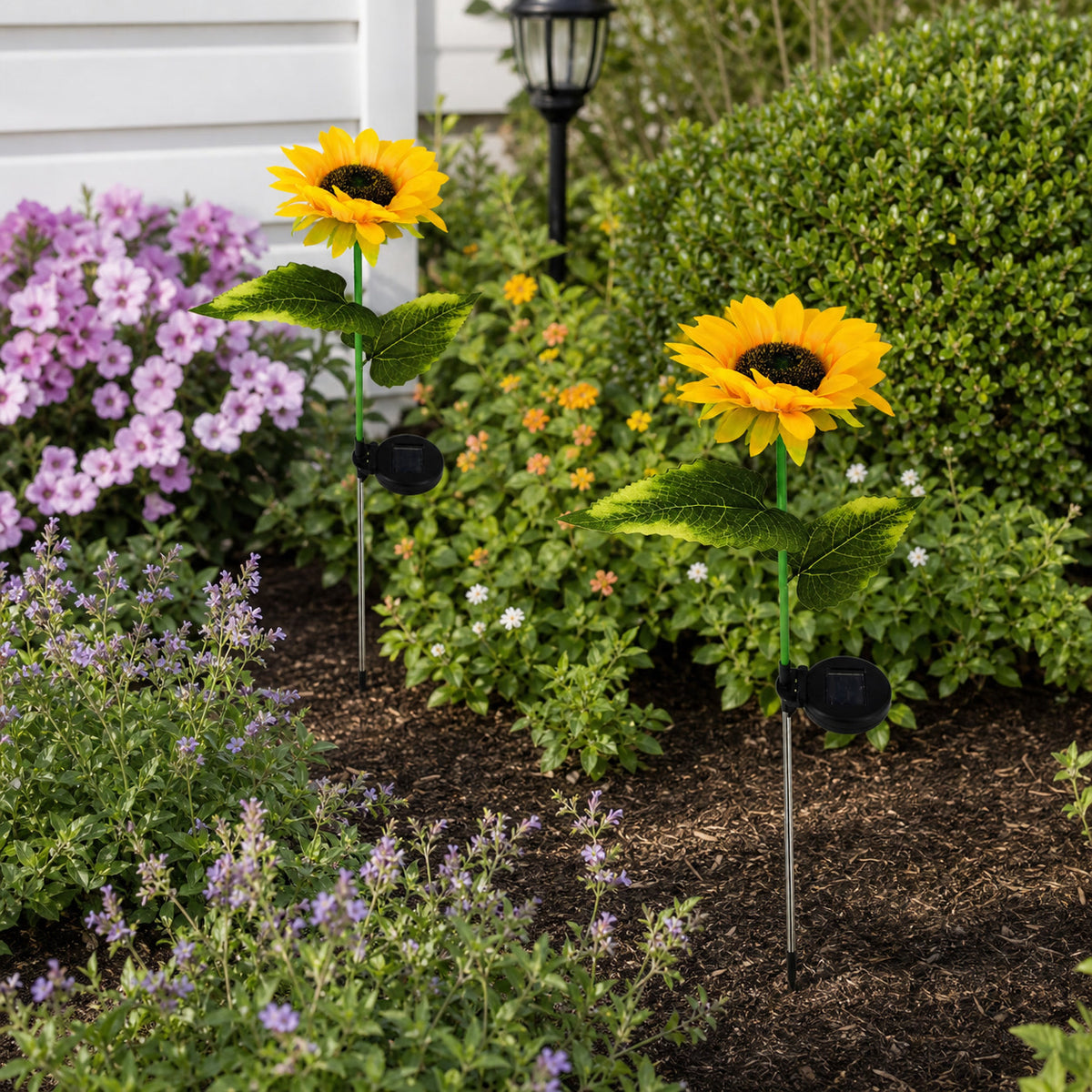 Solar sunflower garden lights placed among flowers in a landscaped garden bed
