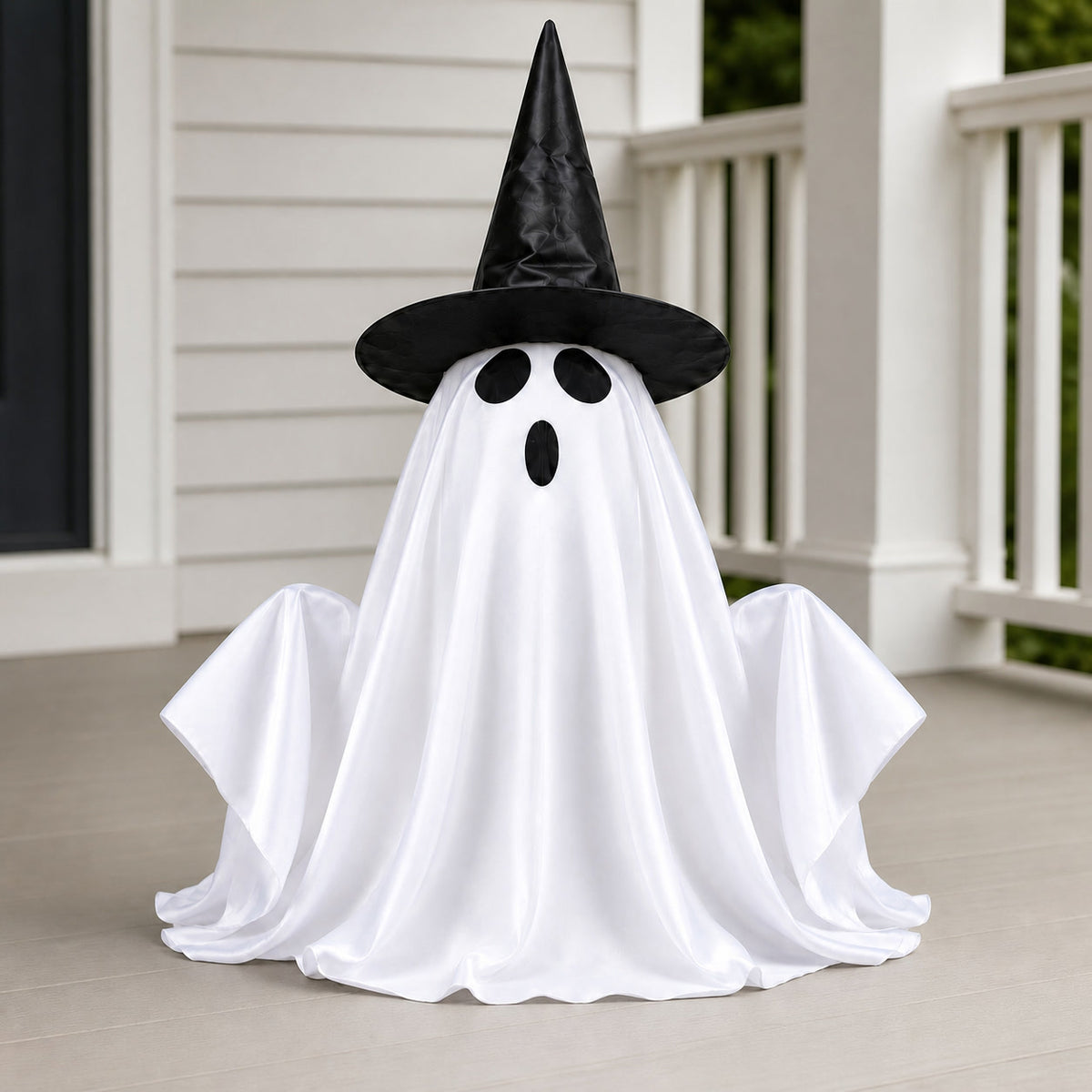 Daylight detail of a white ghost decoration with raised arms and a black witch hat